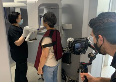 Dental assistant guiding a patient through a panoramic X-ray procedure at Avatar Dental while a videographer records the process