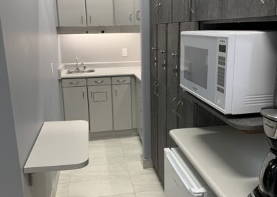 Narrow staff kitchenette at Avatar Dental featuring cabinets, a microwave, coffee maker, and a foldable wall-mounted table