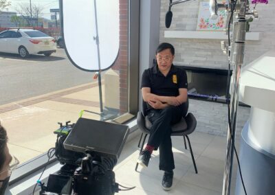 Avatar Dental staff member seated near the clinic's front window during a professional video interview setup with cameras, microphones, and lighting equipment