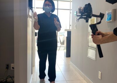Avatar Dental staff member walking down a hallway during a video shoot, with a camera operator filming the scene near the clinic entrance