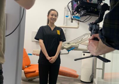 Dental staff member in black scrubs being filmed in a treatment room at Avatar Dental, with professional video and audio equipment in view