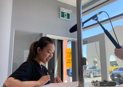 Avatar Dental team member at the front desk during a video shoot, with a microphone positioned above and sunlight streaming through the window